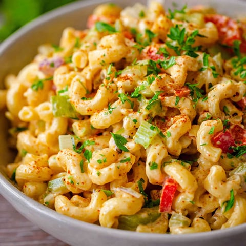 A bowl of Cajun Pasta Salad with various vegetables and herbs.